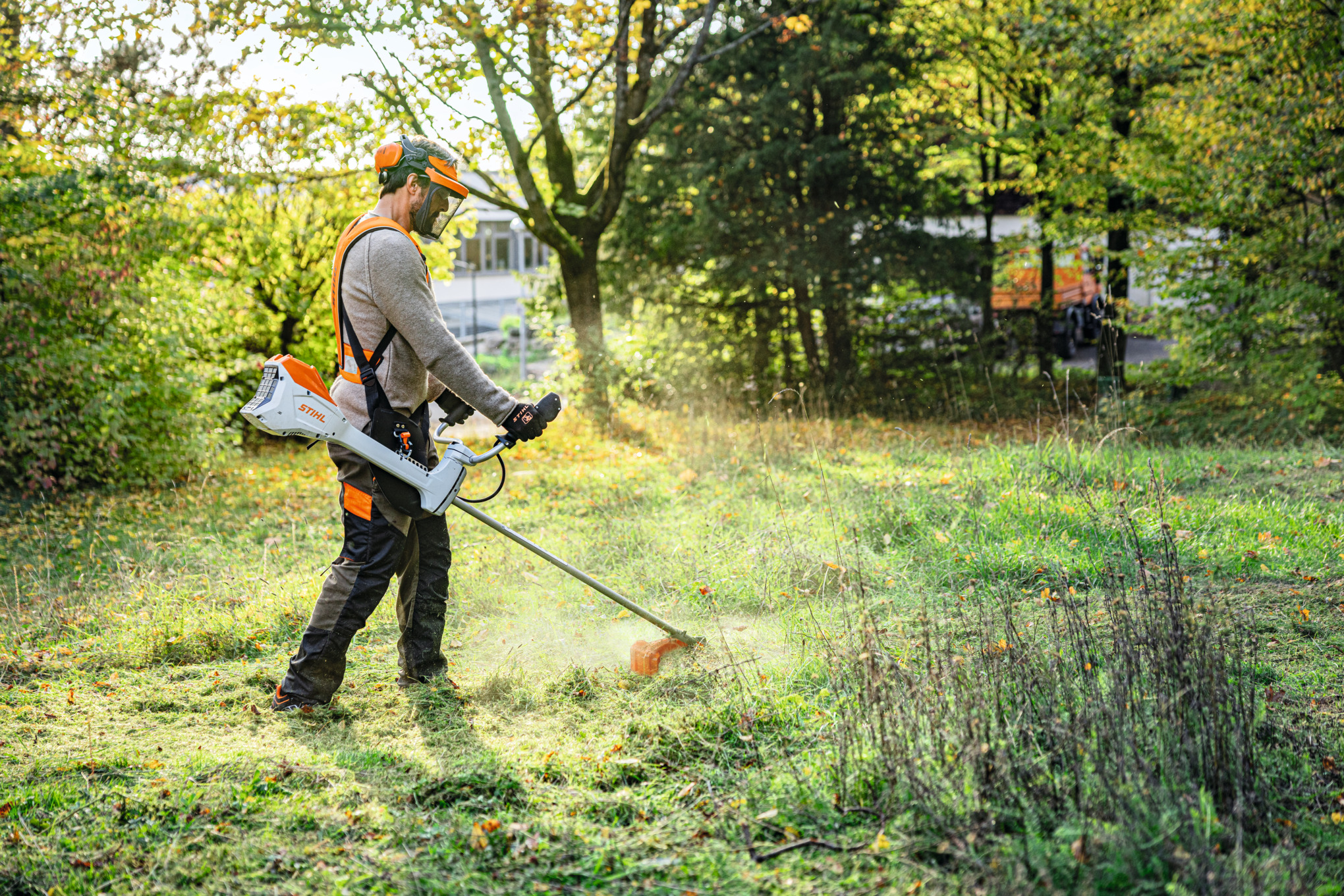 A man mows a green area in a park using the STIHL FSA 200 cordless clearing saw 