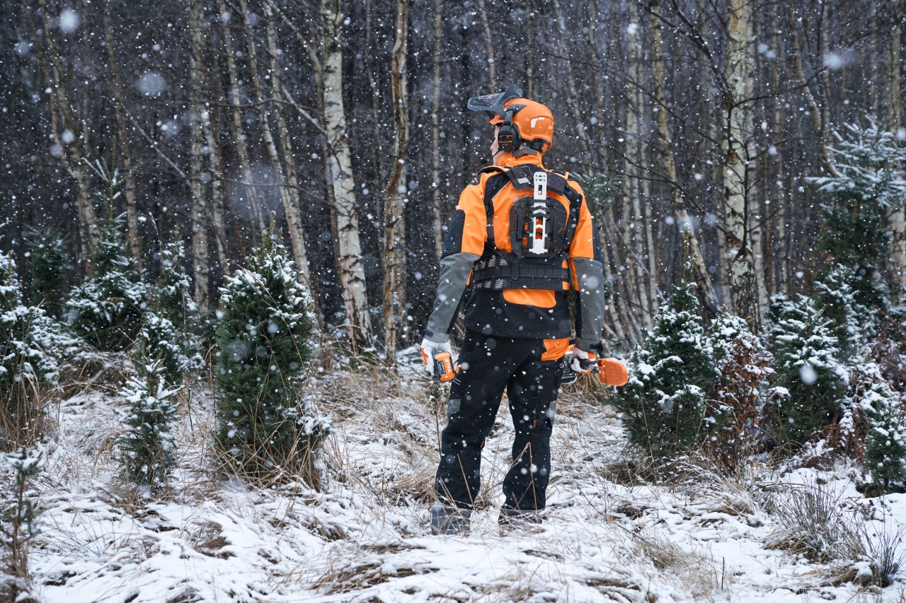 Forestry worker wearing weatherproof PPE in a snowy forest