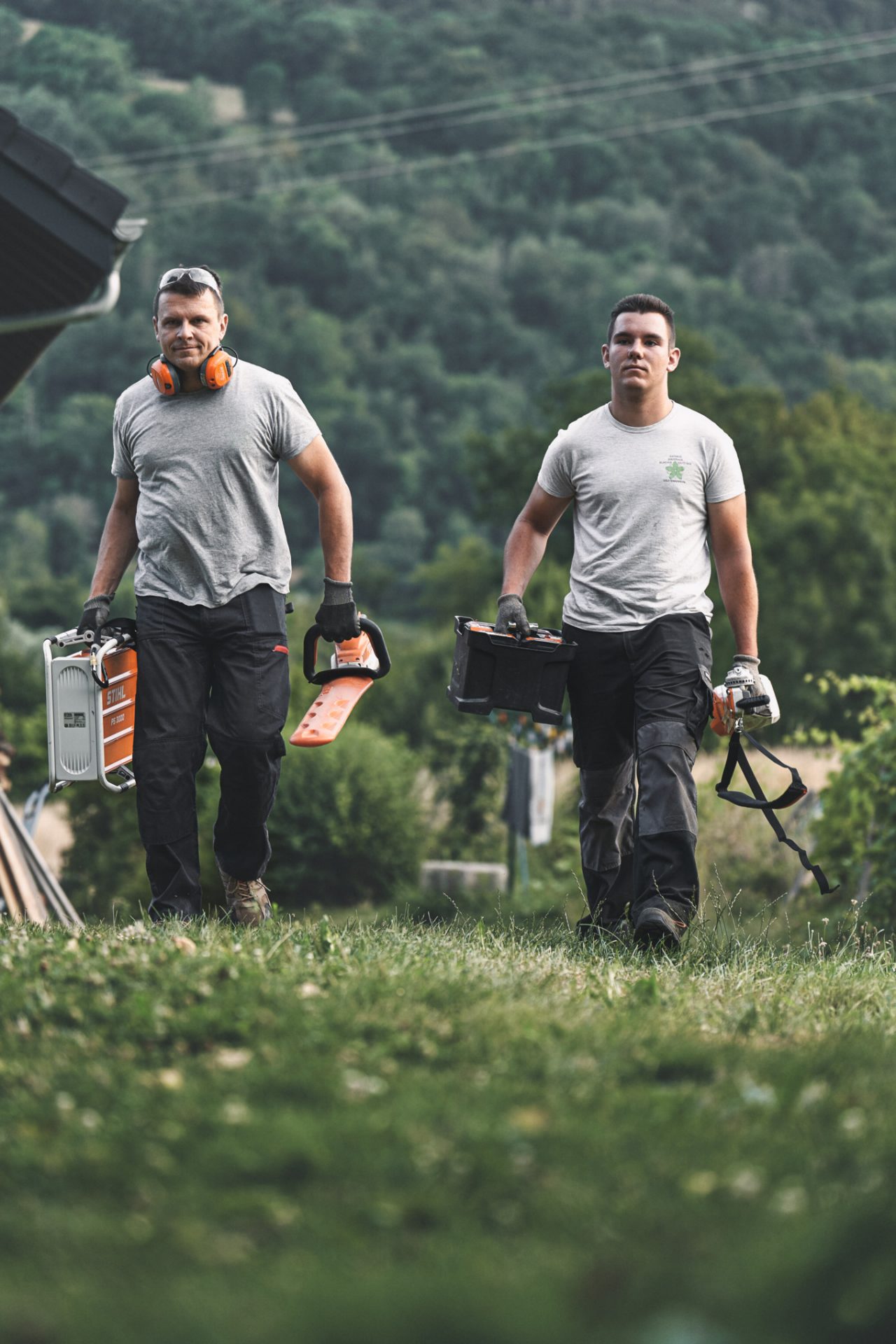 Two professionals walking through a field with STIHL cordless power tools