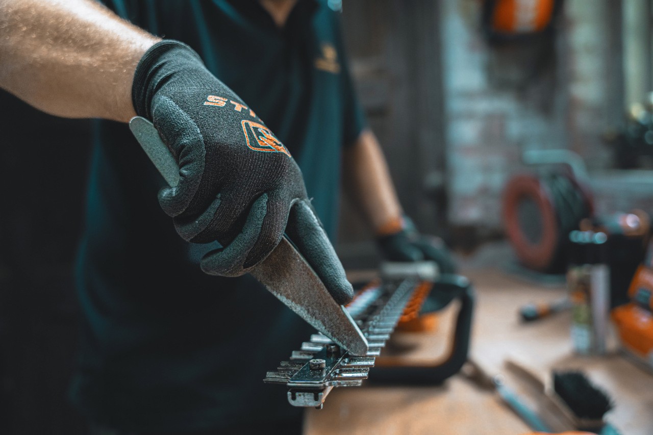 Someone sharpening the blade of a hedge trimmer