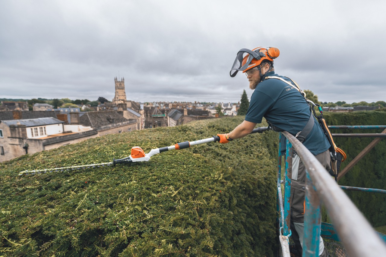 A professional uses a STIHL battery extended hedge trimmer on a lifting platform to cut the top of the hedge at Bathurst Estate