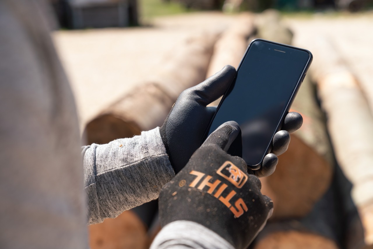 Person with smartphone in hand and STIHL FUNCTION SENSOTOUCH gloves